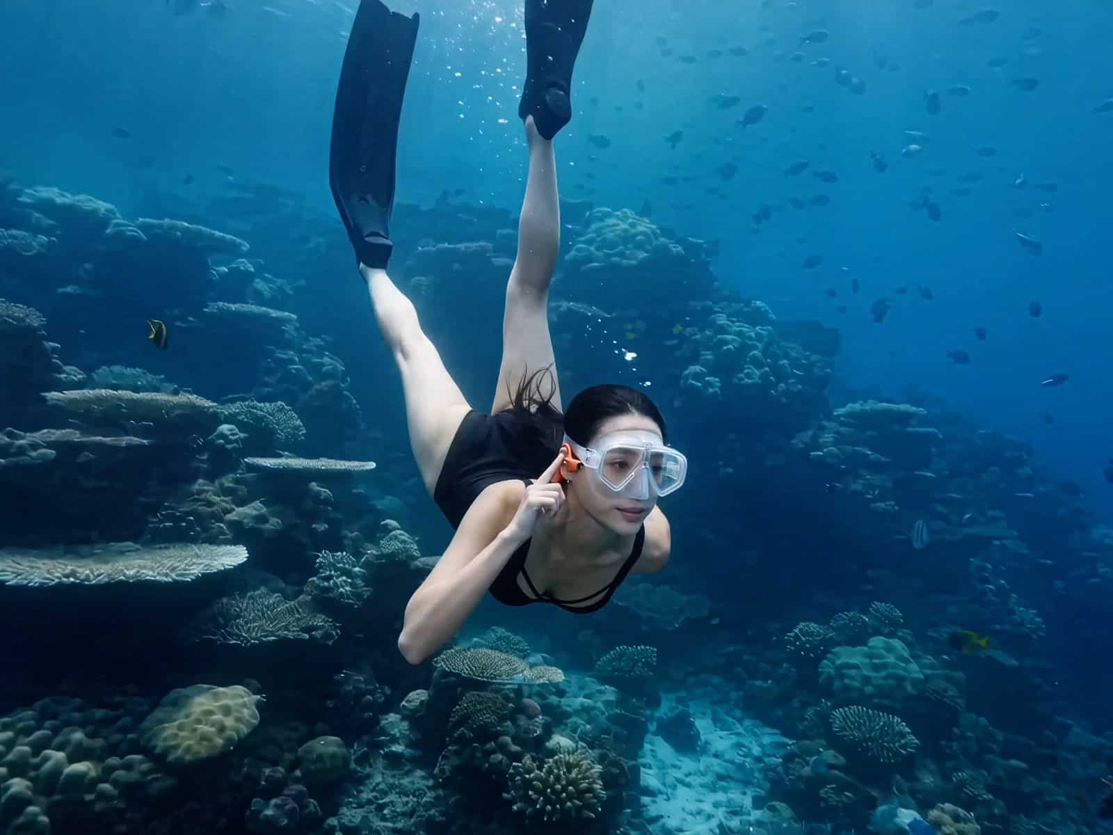 Freediver in a mask and fins swimming above a coral reef in clear blue water