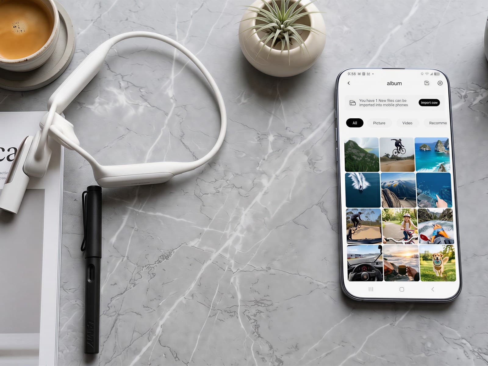 MusicCam Pro headset coiled on a marble desk beside a smartphone showing a grid of captured clips, a coffee cup and small potted plants