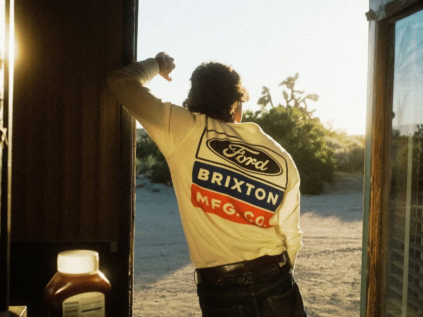 Model in a doorway at golden hour wearing the Ford Service Dept Waffle T-Shirt, back print lit from behind