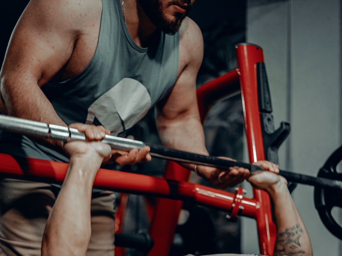 A personal trainer spotting a client on the barbell during a bench press