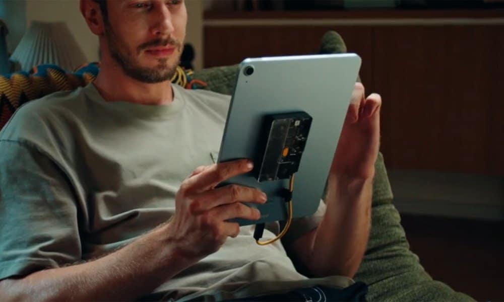 SHARGE Disk Pro 2 magnetically attached to the back of a tablet held by a man sitting on a couch