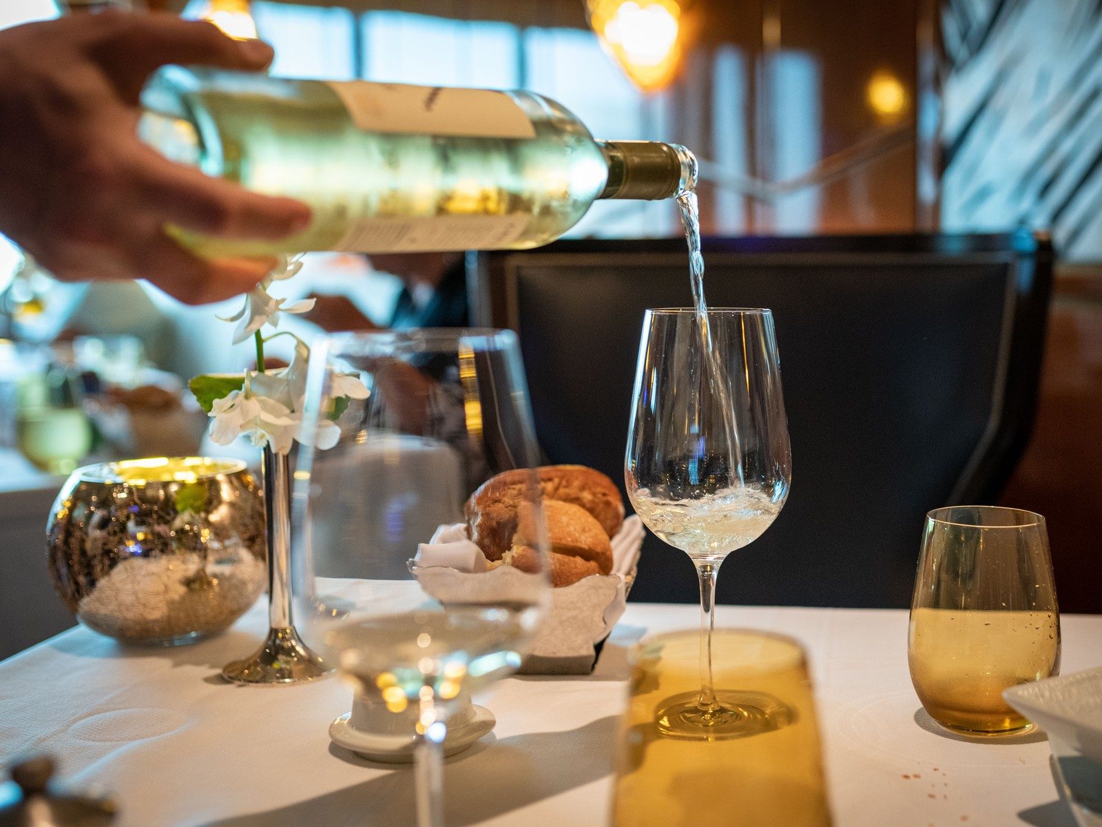 Wine being poured into a glass at a set dining table