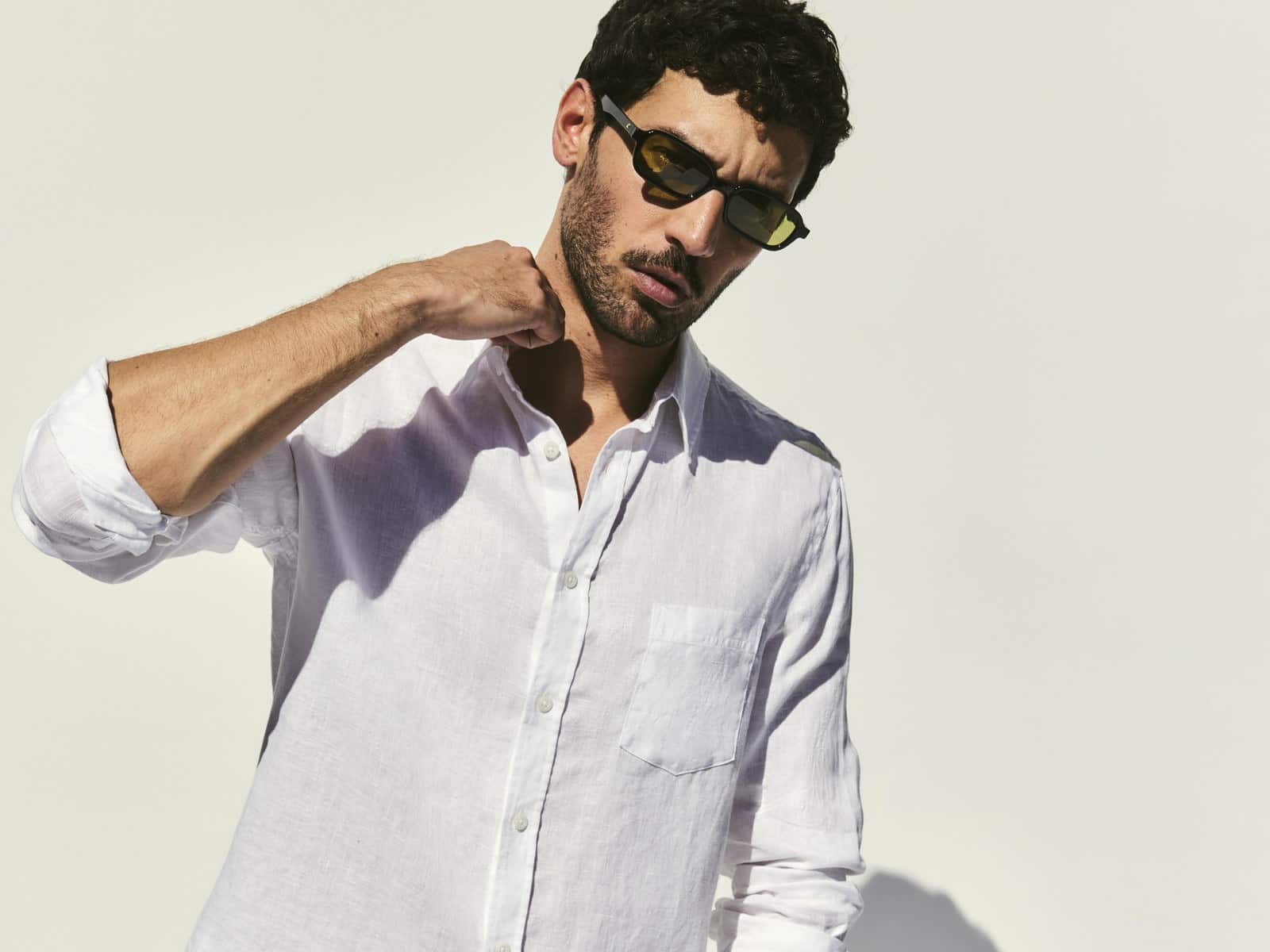 A man in sunglasses wearing a white linen shirt and tan linen pants from the Sportscraft spring-summer campaign