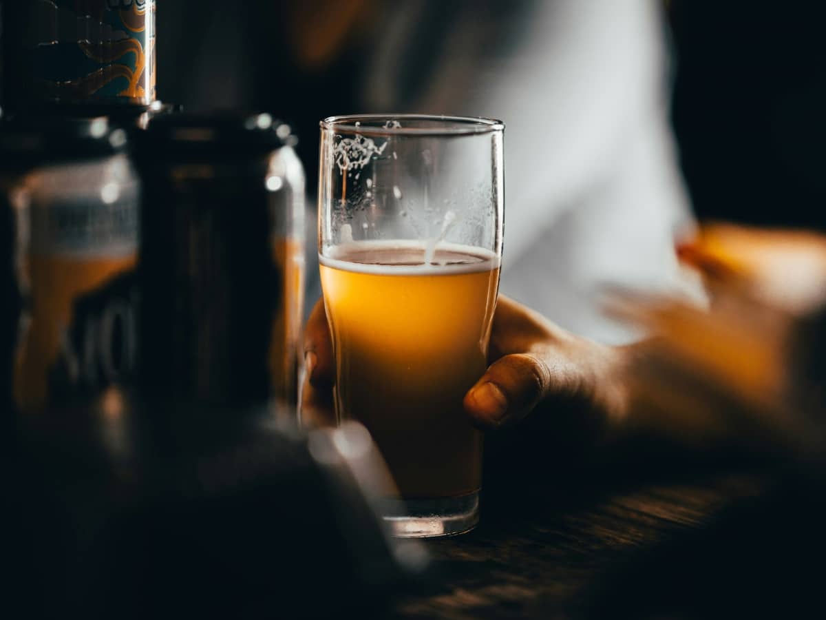 A man's hand holding a pint of beer