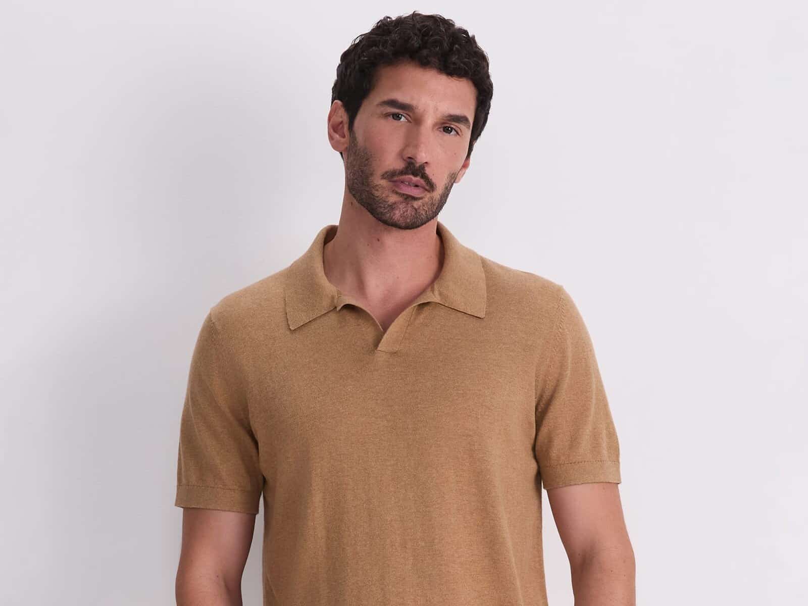 A man wearing the Sportscraft Ojas Knit Polo in Kelp with tan pants