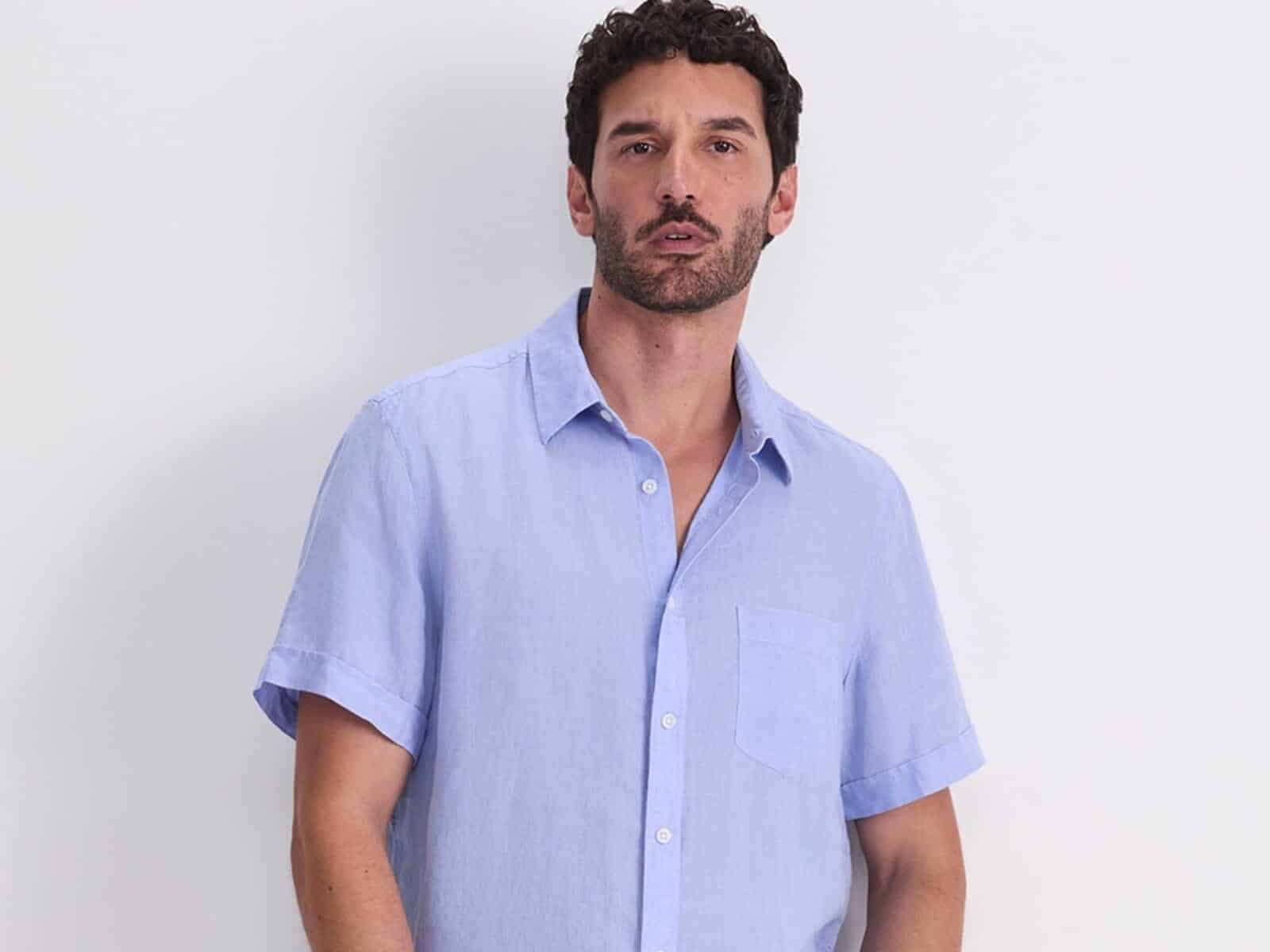 A man wearing the Sportscraft Short Sleeve Delave Linen Shirt in Light Blue with navy pants