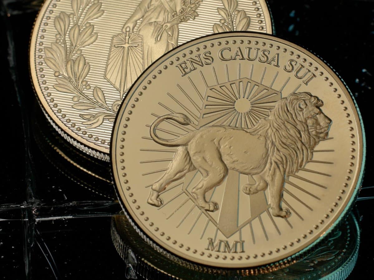 Two gold Continental coins from the John Wick Poker Set, one showing a lion and the words Ens Causa Sui