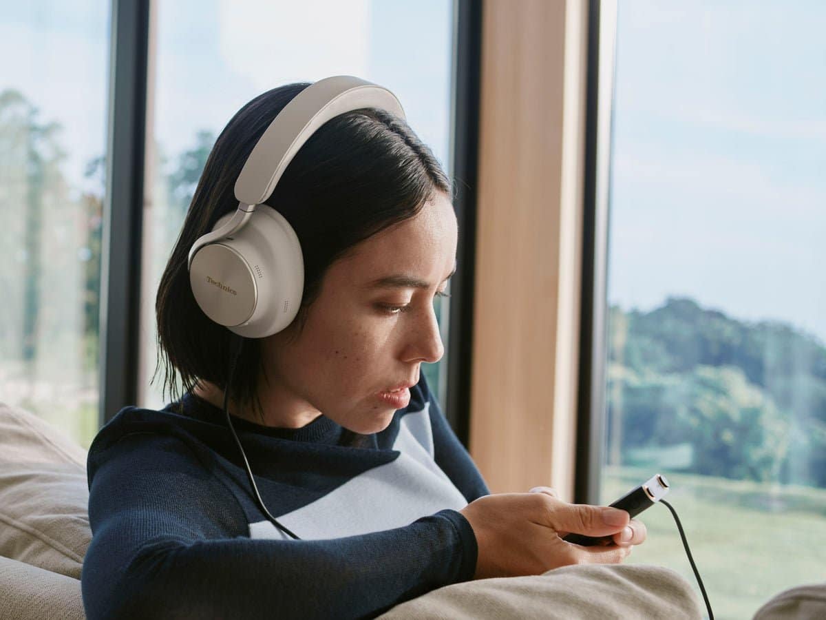 Woman listening to Technics EAH-A1000 headphones over a cable connected to her phone