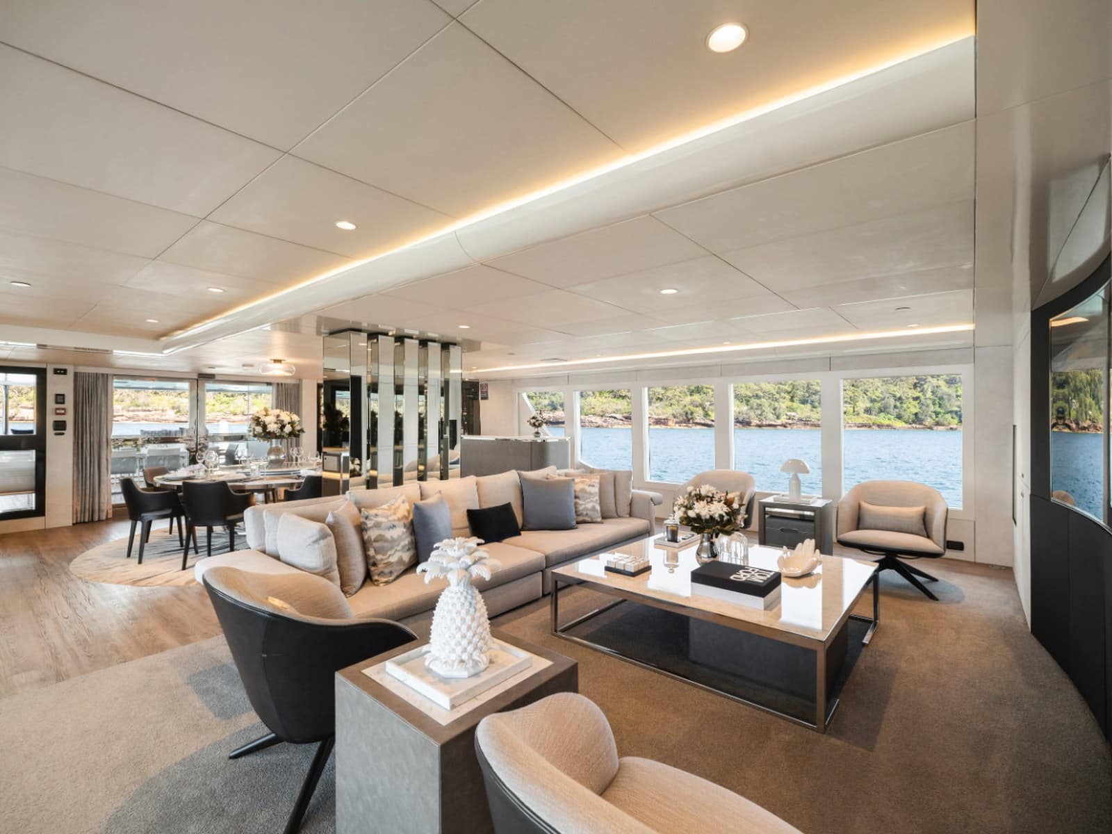 The main saloon aboard Evolution with lounge seating, a dining table and harbour views