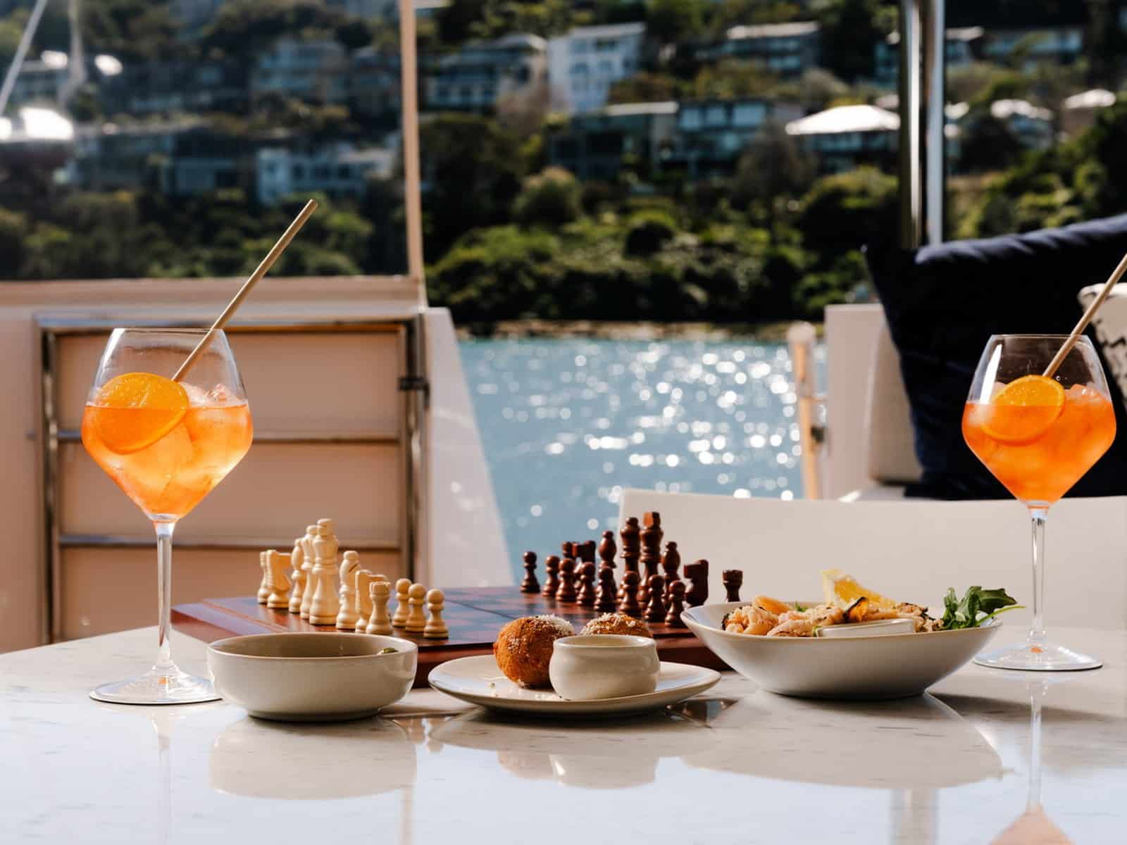 Spritz cocktails and canapés served on the deck of Evolution with the harbour behind