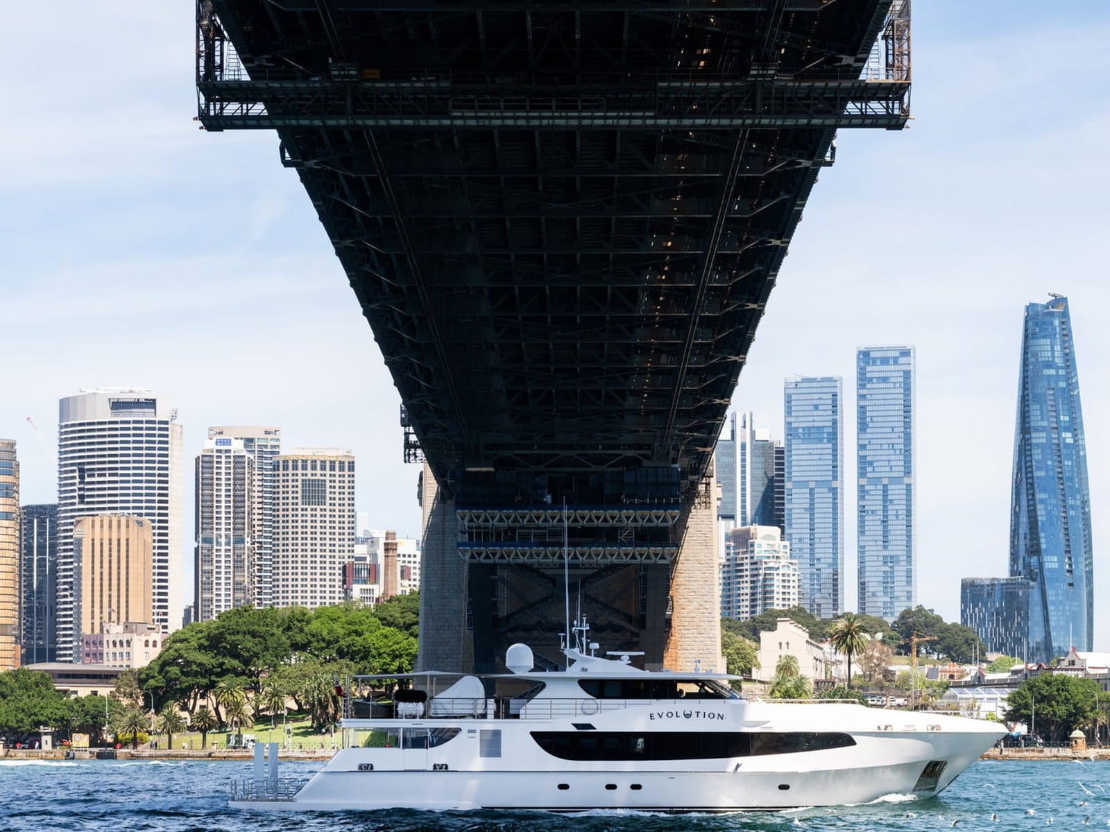 Evolution cruising beneath the Sydney Harbour Bridge with the city skyline behind