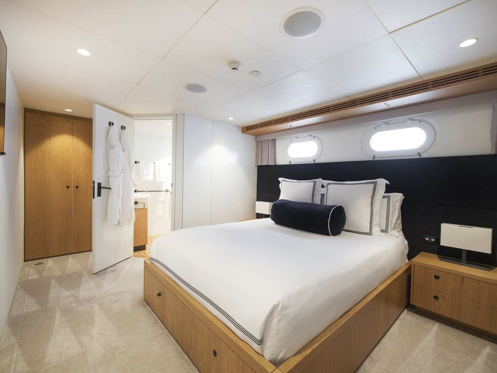 An ensuite guest cabin aboard Evolution with a double bed and portholes