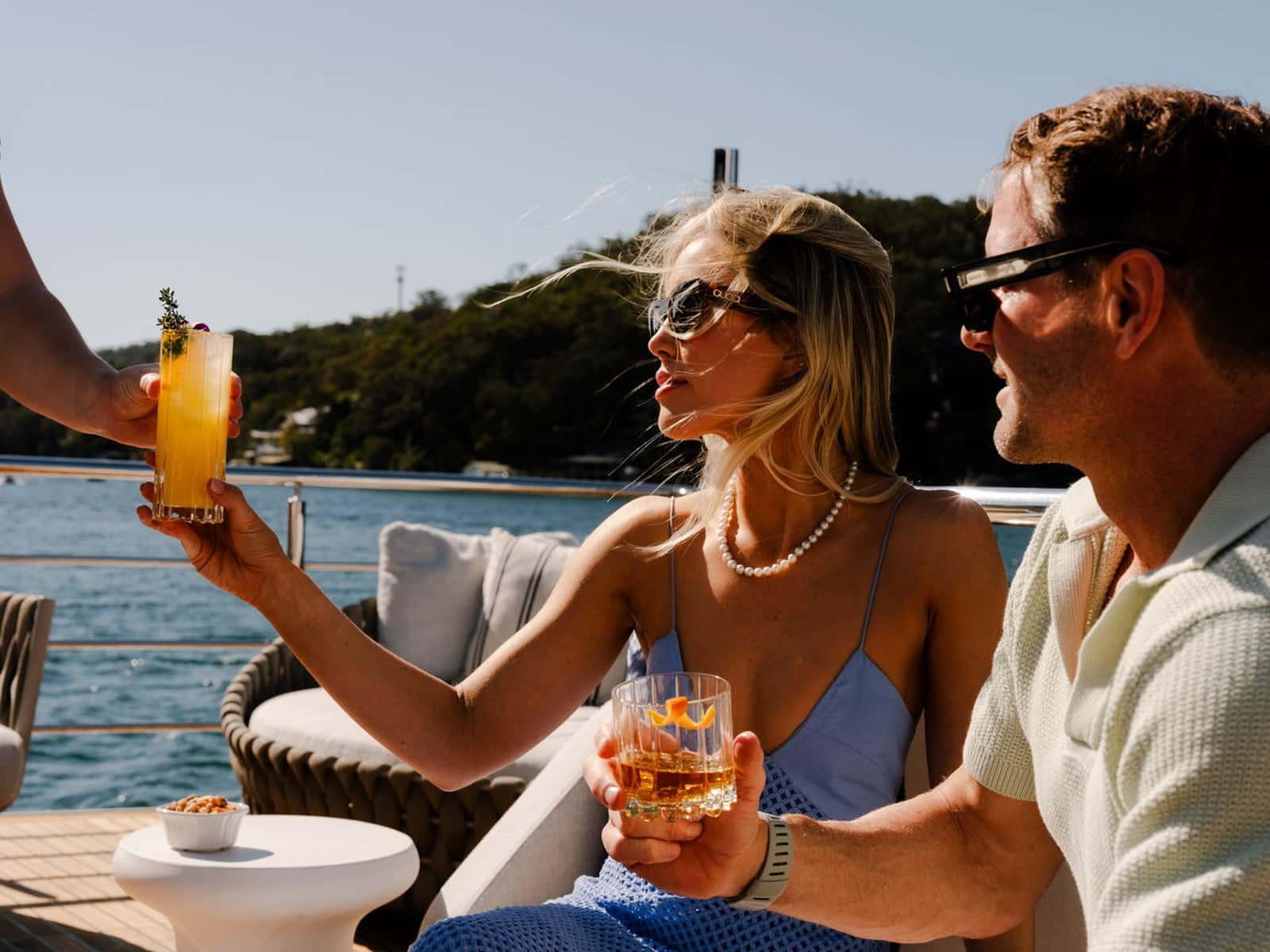 Guests toasting with cocktails on the aft deck of Evolution on Sydney Harbour