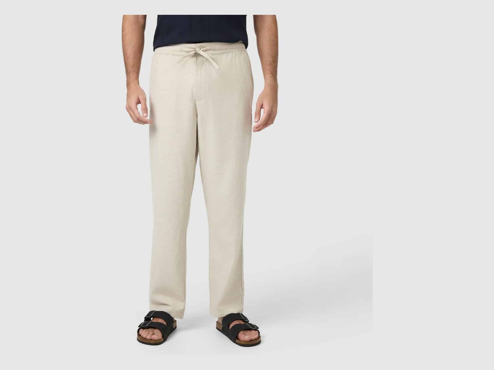 The Connor Cabana Linen Blend Pant in Sand worn with a navy top and black slide sandals