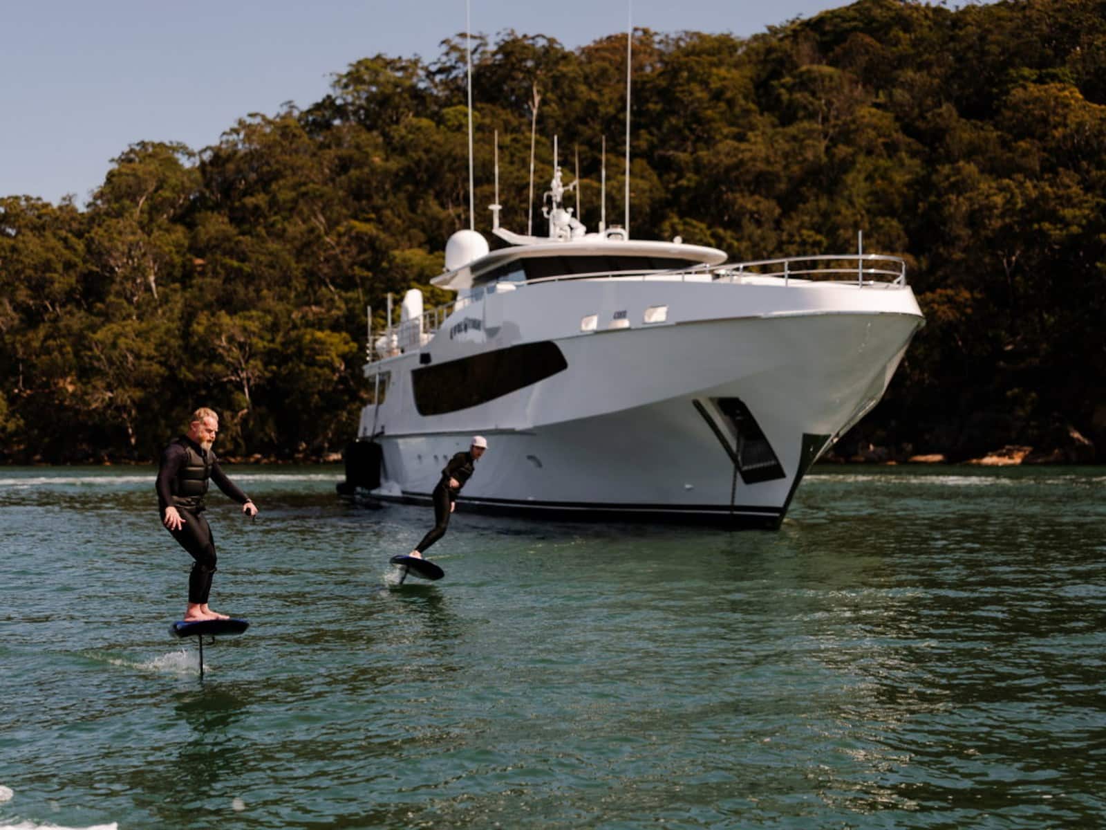 A rider on a Fliteboard skimming past Evolution moored in a quiet Pittwater bay
