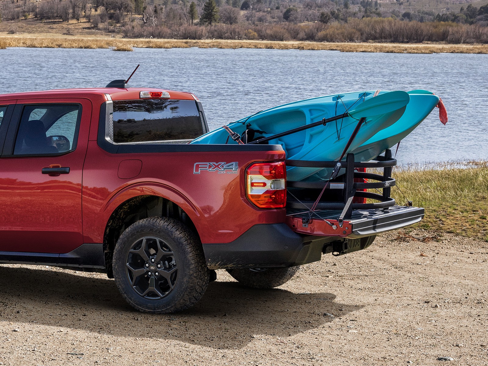 Ford Maverick carrying kayaks on a bed rack by a lake